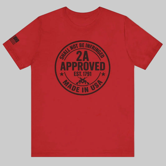 Red ‘2A Approved – Shall Not Be Infringed’ t-shirt with circular stamp graphic and American flag on the sleeve on a grey background.