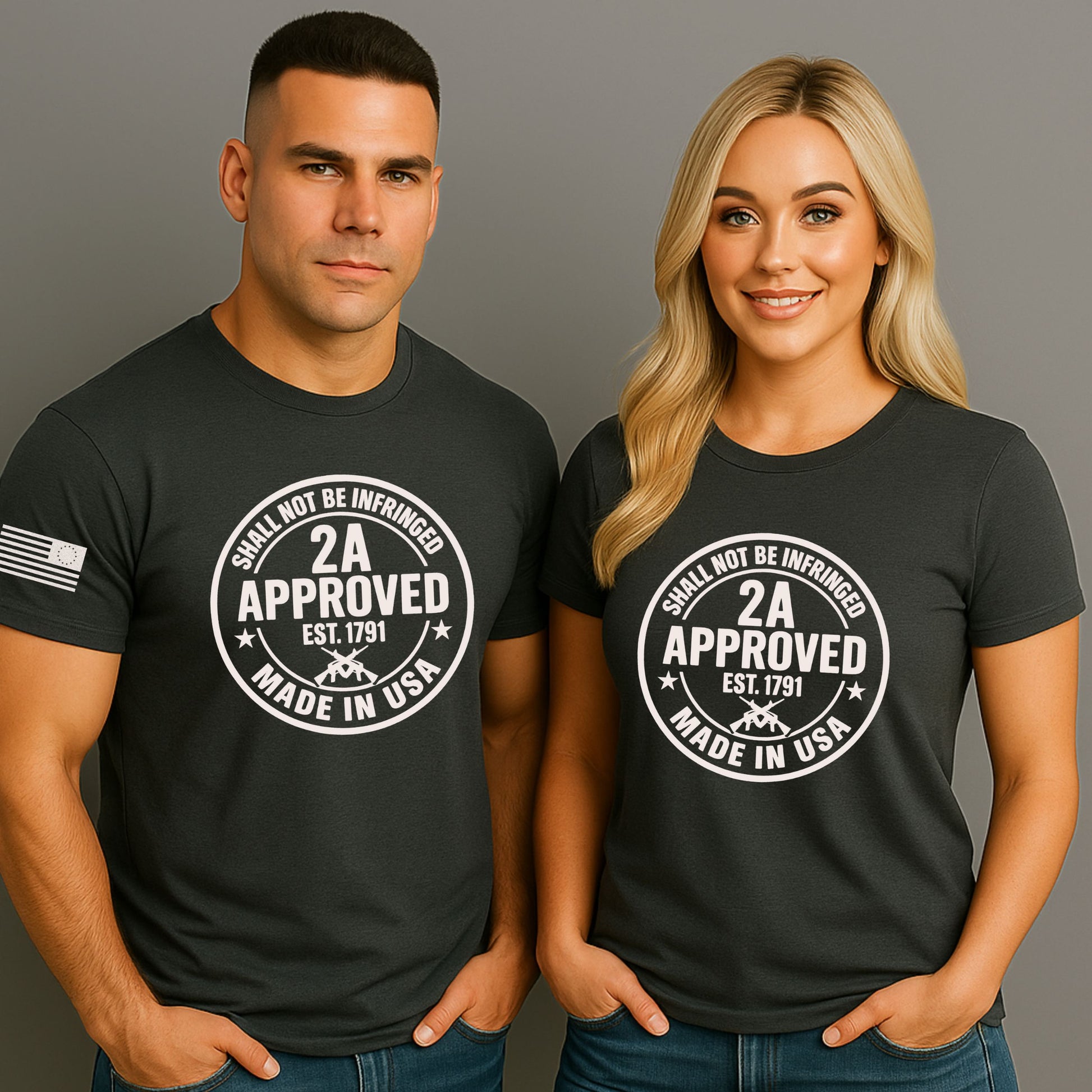 Man and woman wearing charcoal black ‘2A Approved – Shall Not Be Infringed’ t-shirts with circular stamp graphic and American flag on the sleeve, on a gray studio background